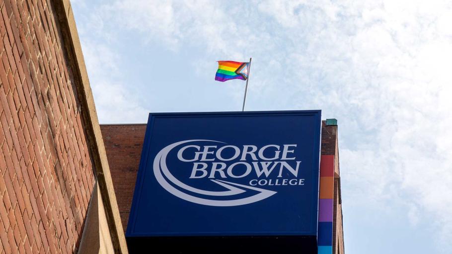 Pride Flag flying over George Brown College sign at 200 King Street East.